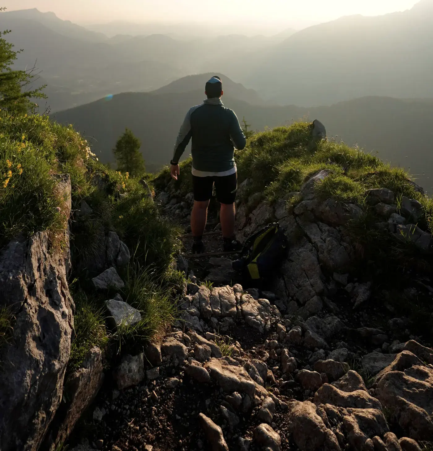 Andreas Hinz steht bei Sonnenaufgang auf einem Berggrat und blickt über gestaffelte Bergketten ins Tal.